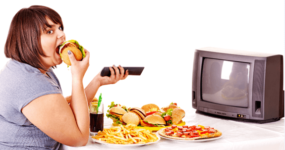 Young woman having burger sitting in front of TV